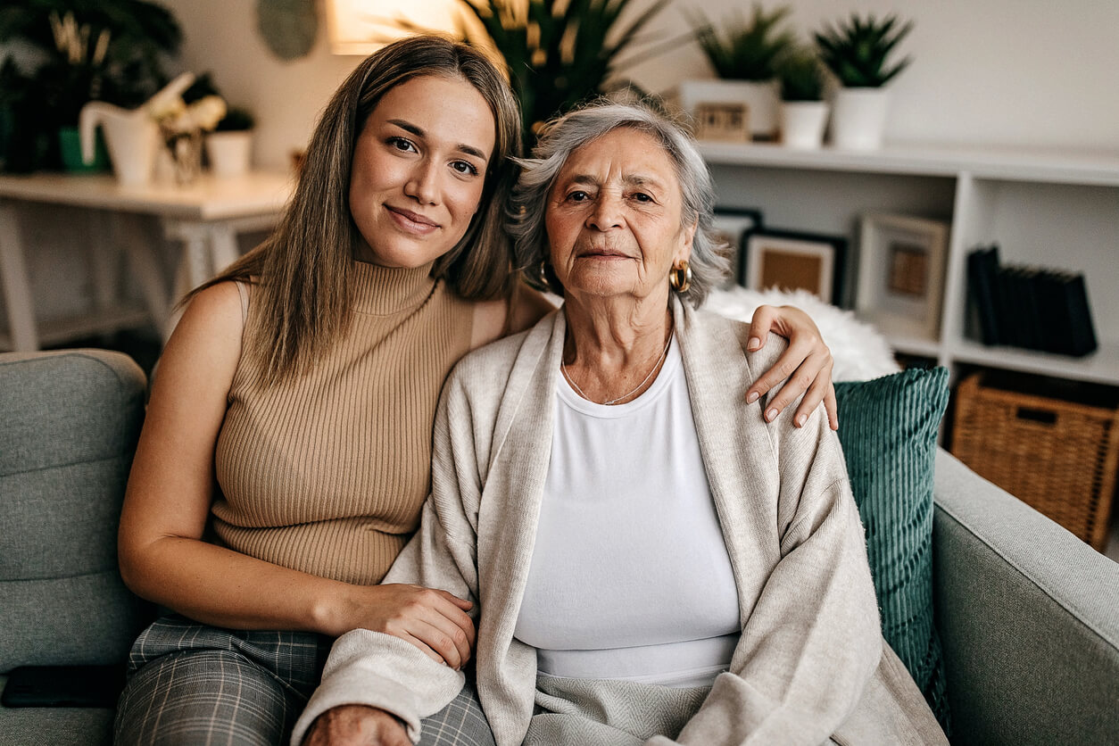 A caregiver puts her arm around an older woman interested in clinical research for autoimmune diseases.