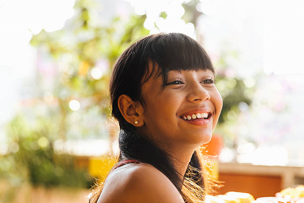 A young girl with a rare disease smiles while sitting outdoors.