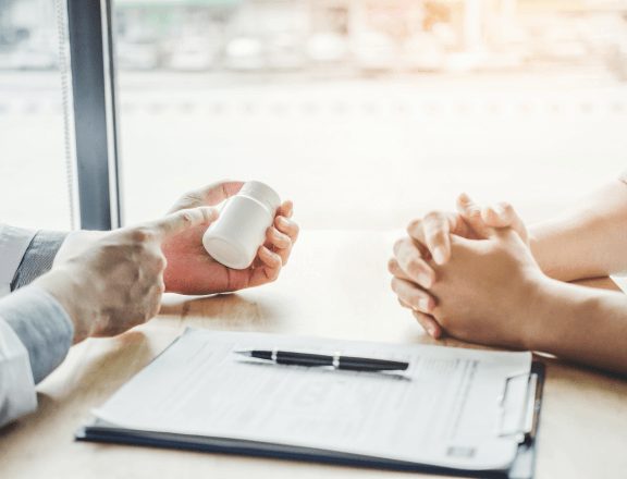 Doctor holding and showing a bottle of medicine to a patient