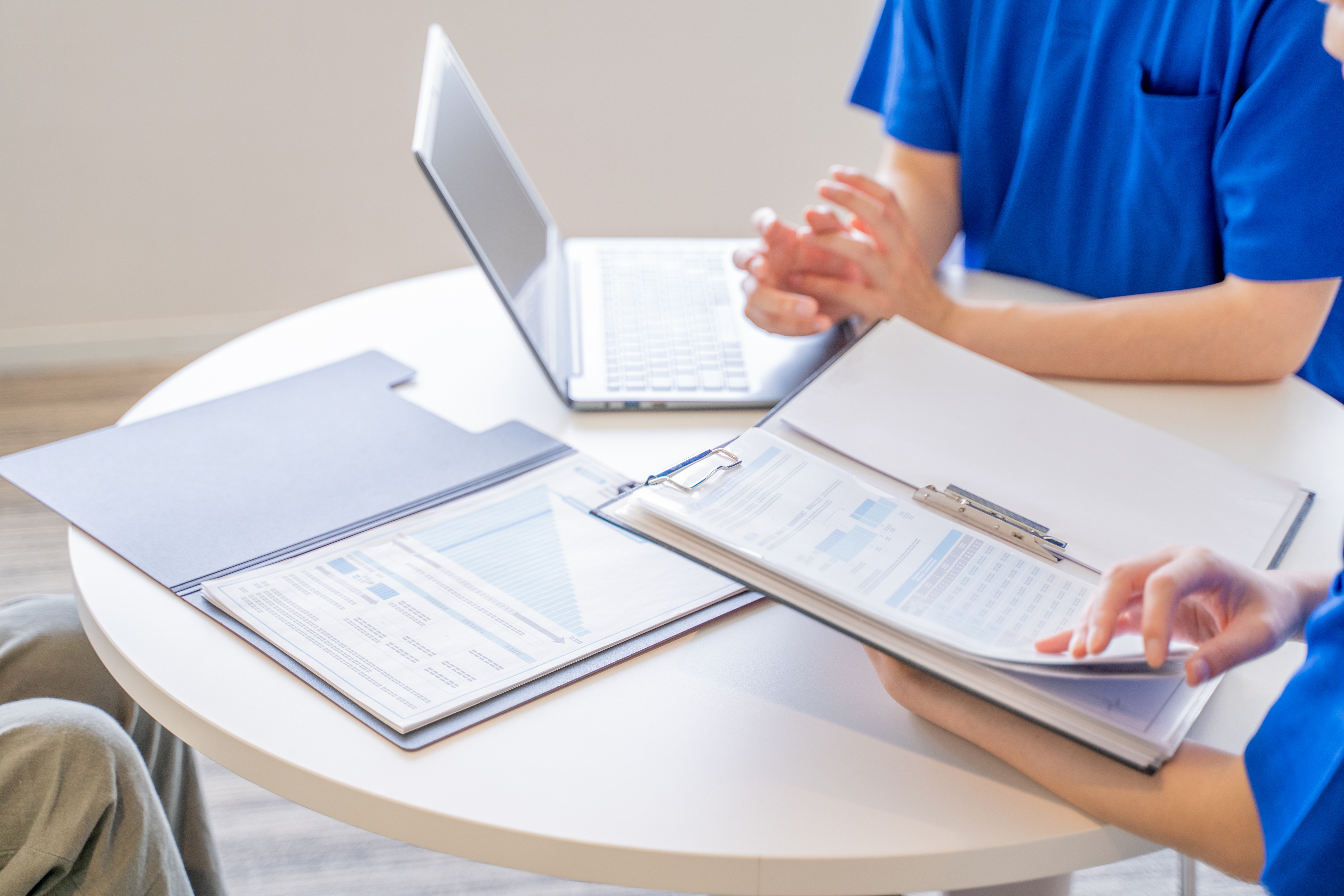 Clinicians reviewing printed charts and a laptop at a round table